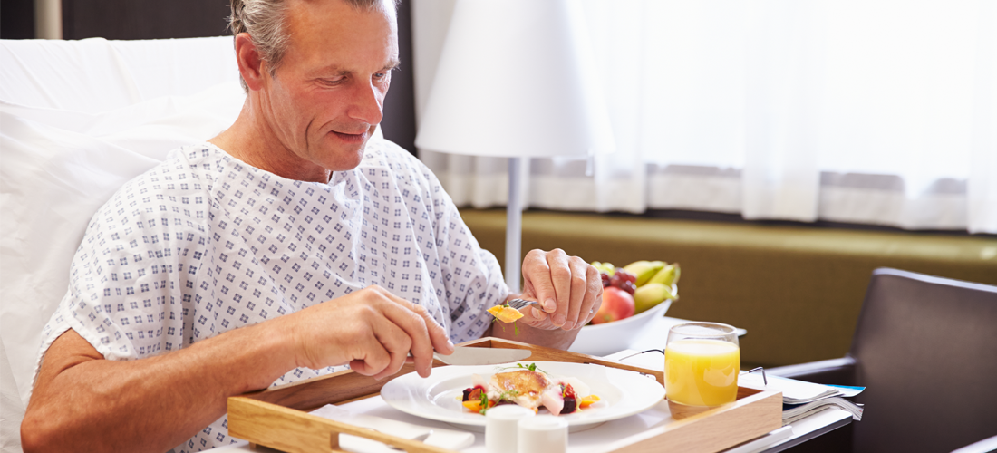 Male Patient In Hospital Bed Eating Meal From Tray | Doylestown Health